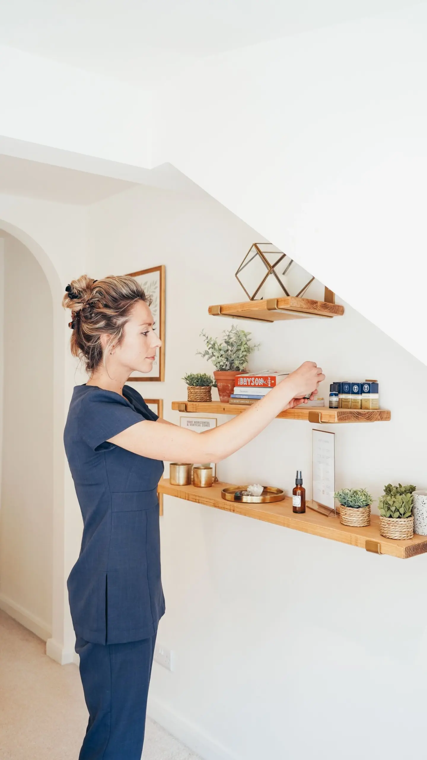 Ellie sorting items on wooden shelves in the Rutland Reflexology clinic treatment room