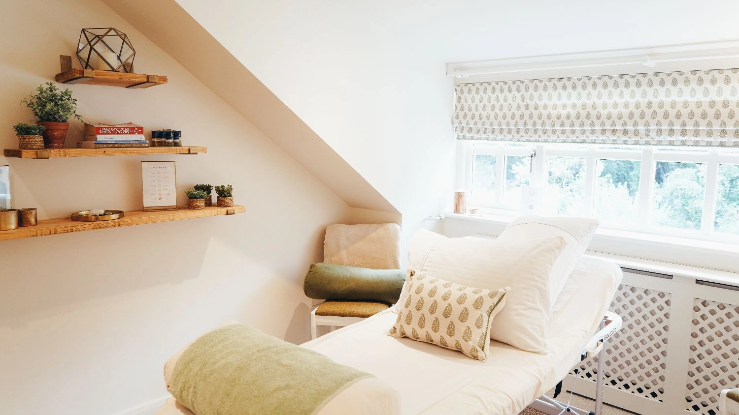 Rutland Reflexology treatment room with a window, wooden shelves with items on, and treatment bed